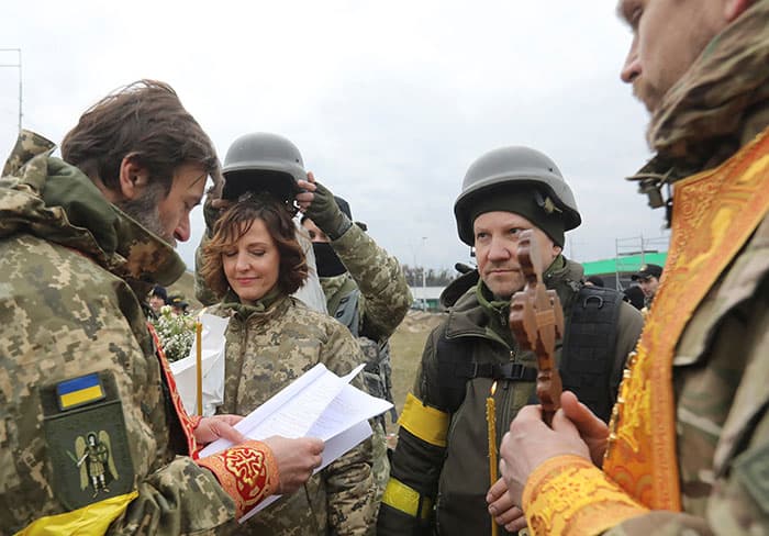 Members of the Ukrainian Territorial Defense Forces Lesia Ivashchenko and Valerii Fylymonov listen to a priest at their wedding at a checkpoint in Kyiv March 6, 2022, during the Ukraine-Russia conflict. (CNS photo/Mykola Tymchenko, Reuters)