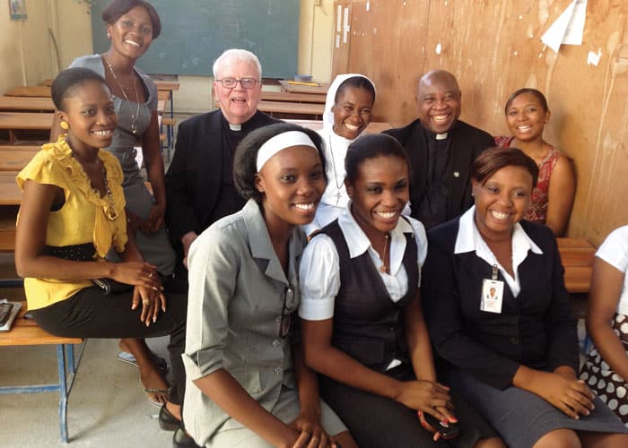 38-42-Fr-St-Vil-02 On a trip to Haiti in 2013, Maryknoll Fathers Michael Duggan and Romane St. Vil visit a school the Maryknoll Fathers and Brothers helped rebuild. (Courtesy Romane St. Vil/Haiti)