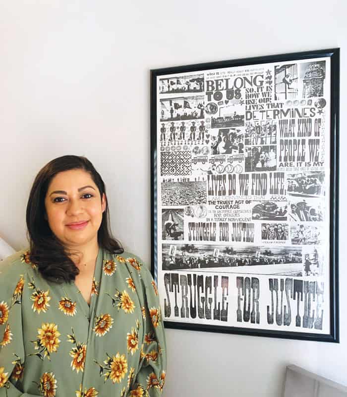 Karen Luna, young adult ministry coordinator for the Archdiocese of Los Angeles, smiles next to a poster by Catholic painter John A. Swanson. (Courtesy of Karen Luna/U.S)