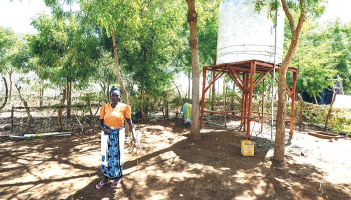A woman at the St. John the Baptist mission stands near a water storage tank that is part of a Maryknoll project to drill wells in the drought-ravaged area of Kibwezi in Kenya. (Gregg Brekke/Kenya)
