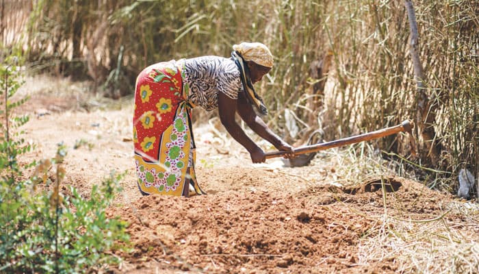 A woman tills the soil, preparing to plant corn on the grounds of the St. John the Baptist mission near Kibwezi, Kenya, where the Maryknoll Society funds a food and water project. (Gregg Brekke/Kenya)