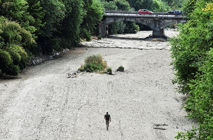 A man walks on the dry riverbed of the Sangone River, a tributary of the Po River, in Beinasco, Turin, Italy, June 19, 2022. Italy is experiencing its worst drought in 70 years. (CNS photo/Massimo Pinca, Reuters)