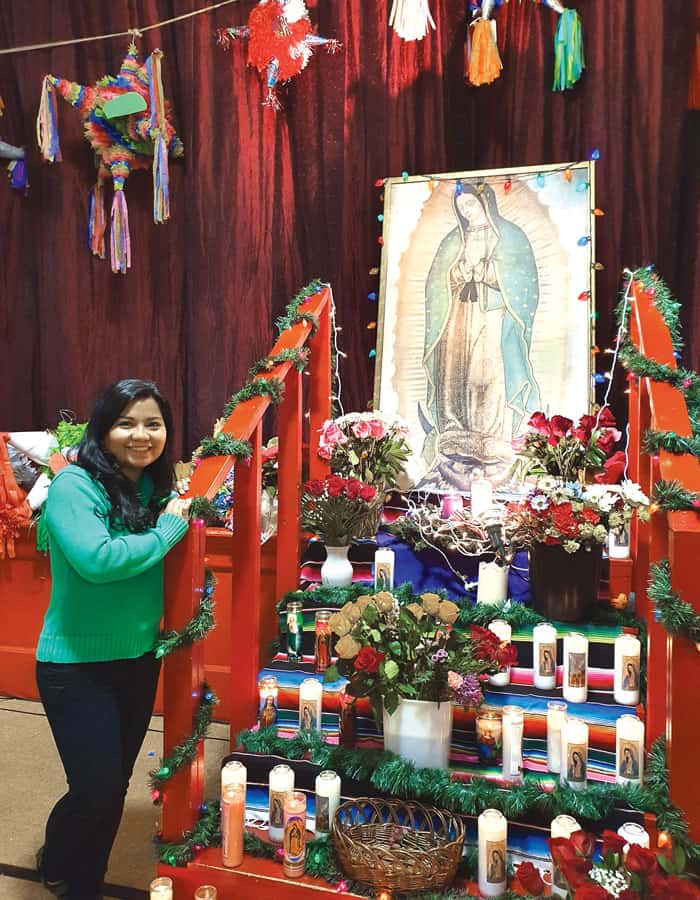Silvana Martinez smiles next to an image of Our Lady of Guadalupe at Sacred Heart Center, which helps to better the quality of migrants’ lives in Richmond, Virginia.