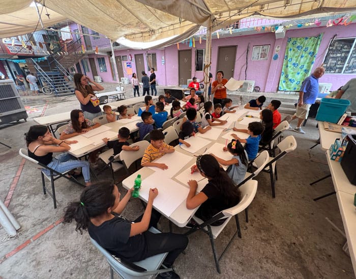 Estefani Crisostomo, (orange shirt) one of our YAE community members who is a family and marriage therapist, led children at the shelter through an art project to explore emotional barriers. (Courtesy of Maryknoll YAE/Mexico)