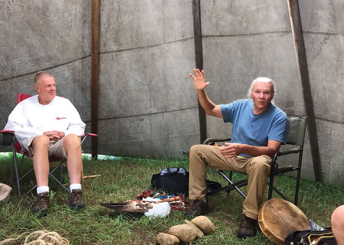 Inside the teepee, Deacon Dennis Holley (left), who helped organize the trip, listens with other participants as Chief Gary Cheeseman tells the Lakota creation story. (Scott Giblin/U.S.)