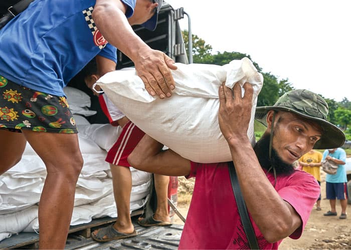 Workers in Mae Sam Laep village in Thailand carry bags of rice for displaced people in Myanmar to boats on the Salween River, which separates the two countries. (Paul Jeffrey/Thailand)