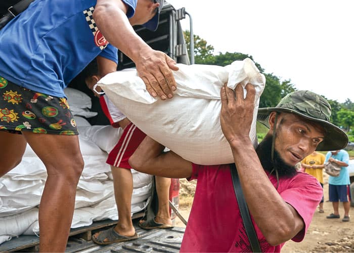 10-15-Fr-Barth-02 Workers in Mae Sam Laep village in Thailand carry bags of rice for displaced people in Myanmar to boats on the Salween River, which separates the two countries. (Paul Jeffrey/Thailand)