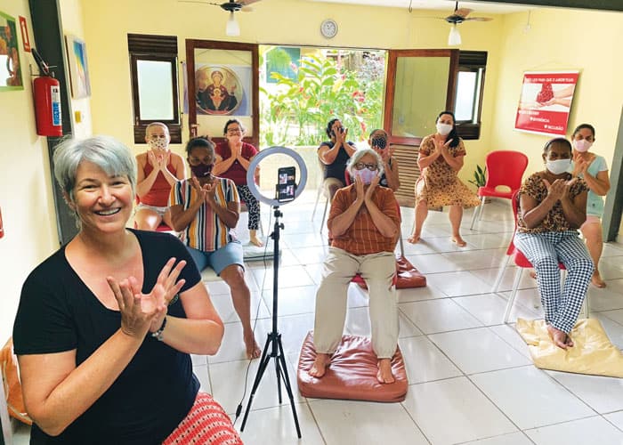 40-44-Economic-Justice-Afya-03 Maryknoll Lay Missioner Kathy Bond (in front), a holistic health educator, leads a chair yoga class at AFYA. Bond teaches cooperative members and other program participants therapeutic skills they can then offer to others. (Courtesy of Kathy Bond/Brazil)