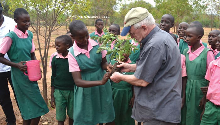 Maryknoll Superior General Father Lance Nadeau helps students plant trees at Malembwa Primary School in southeast Kenya, where Maryknoll assists survivors of climate change. (Moses Njagua Gitahi/Kenya)