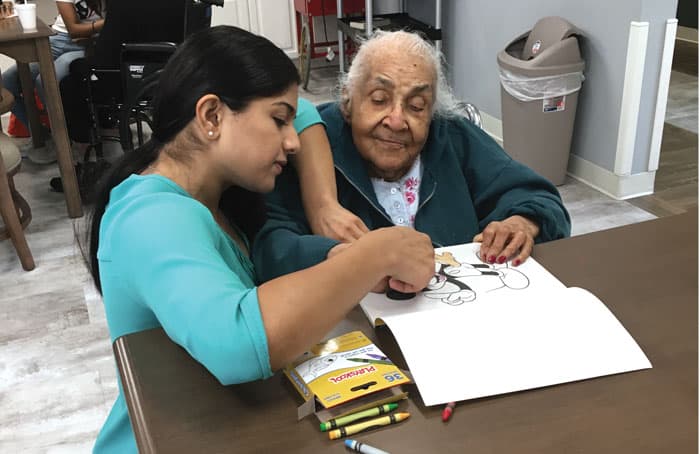 52-55-Serving-the-Poor-01 Christie (left), the wife of Mesias Pedroza, engages in recreational activities with a nursing home resident. The visit is part of Matthew’s Family Ministries, run by the young couple.
