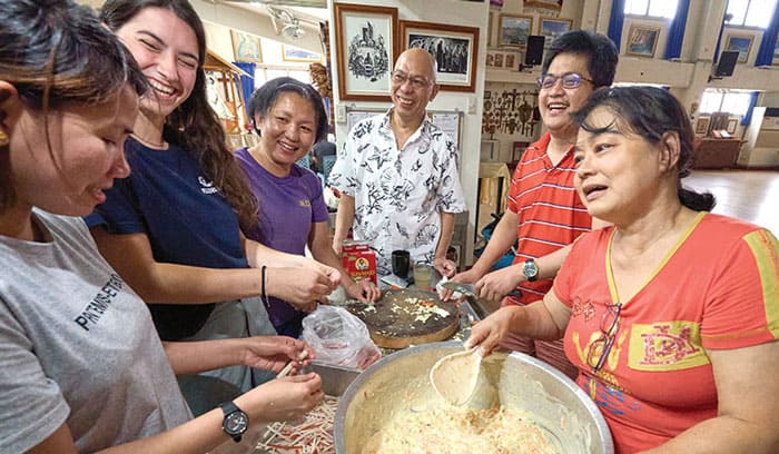 10-15-Joyalito-01 In Taichung, Taiwan, Maryknoll Father Joyalito Tajonera (center) and volunteers prepare a meal in the Ugnayan shelter he founded, which is run like a Catholic Worker house. (Paul Jeffrey/Taiwan)