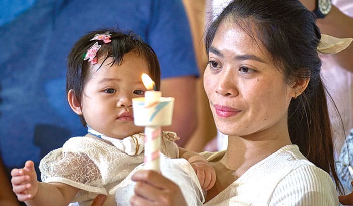 10-15-Joyalito-03 Migrant Alina Querubin, holds her daughter, Hsin yi zoa, after the girl was baptized in the Tanzi Catholic Church in Taichung, Taiwan. Mother and child live at the Ugnayan shelter. (Paul Jeffrey/Taiwan)