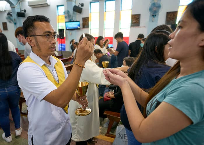 Eucharistic minister Vincent Canlas Manalili distributes Communion to migrant workers. (Paul Jeffrey/Taiwan)