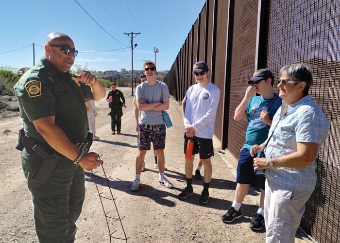 Maryknoll Lay Missioner Deborah Northern (far right) and a group of high school students talk to a Border Patrol agent during an immersion trip. (Courtesy of Deborah Northern/U.S.)