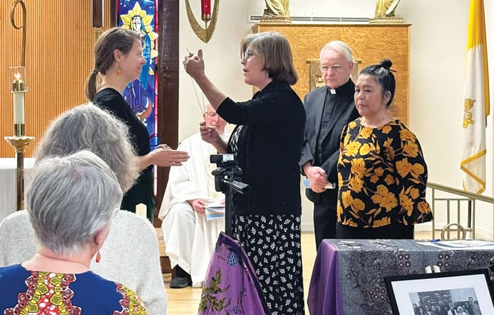24-28-MKLM-Sending-Ceremony-01 Maryknoll Lay Missioners Executive Director Elvira Ramirez confers the mission cross on new lay missioner Sarah Bueter as Maryknoll Father Lance Nadeau and Maryknoll Sister Leonor Montiel look on. (Courtesy of Maryknoll Lay Missioners/U.S.)