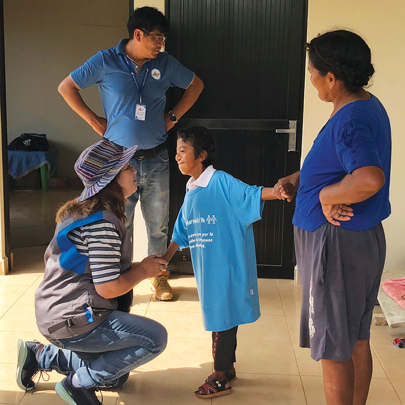 26-31-Joe-Filo-Loney-3 Siles shares a tender moment with Jhon Alex Muñoz as his mother, Doña Benita, looks on. Thanks to physical therapy, Jhon Alex can now walk. (Meinrad Scherer Emunds/Bolivia)