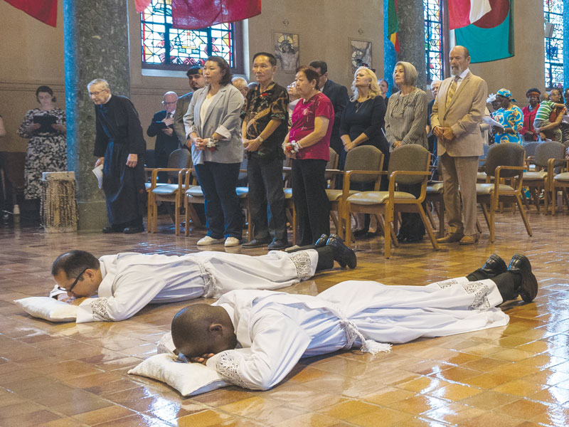 F25-Ordination-2 Ordinands Matthew Sim and Patrick Okok lie prostrate for the Litany of Supplication. The Mass was held at Our Lady Queen of Apostles Chapel. (Octavio Durán/U.S.)