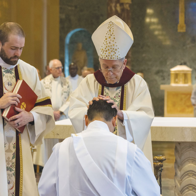 F25-Ordination-3 The ordaining prelate, Bishop Seitz, lays hands on Matthew Sim, ordained a priest along with Patrick Okok on June 7, 2025. (Octavio Durán/U.S.)