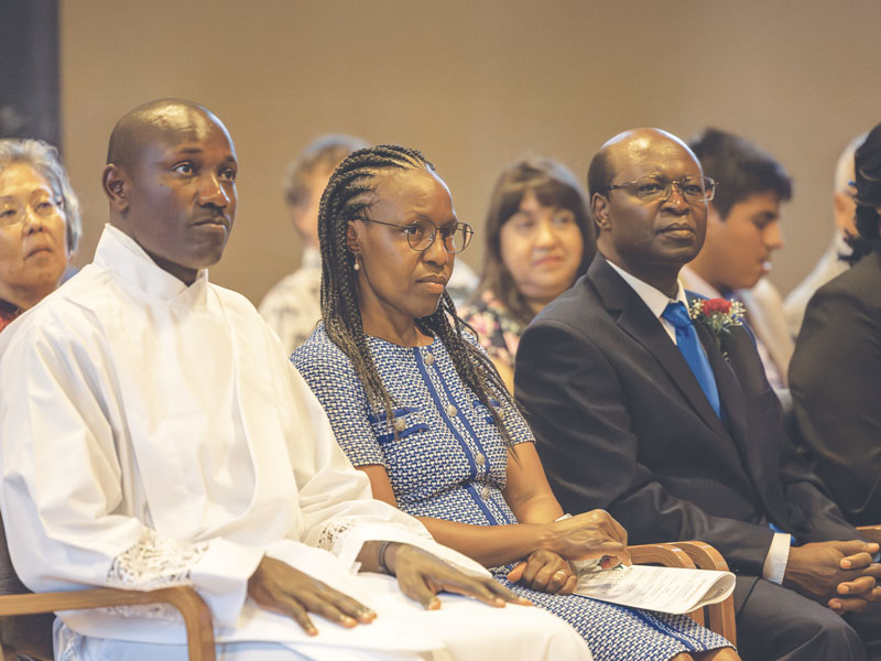 F25-Ordination-5 Patrick Okok, of Kenya, asked Florence and Jospeter Mugambi to represent his parents, who were not given visas to attend the ordination in Ossining, New York. (Adam Mitchell/U.S.)