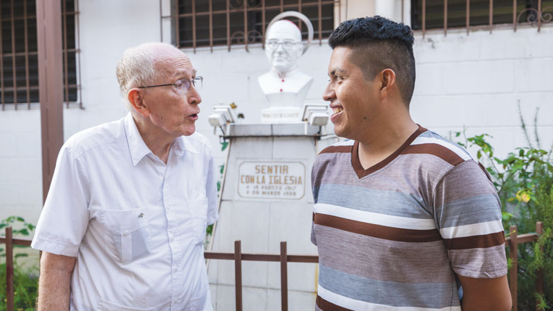 Father Spain chats with Cristo Salvador youth group member Ronald González Cornejo, whose mother and grandmother have served with Maryknollers. (Octavio Durán/El Salvador)