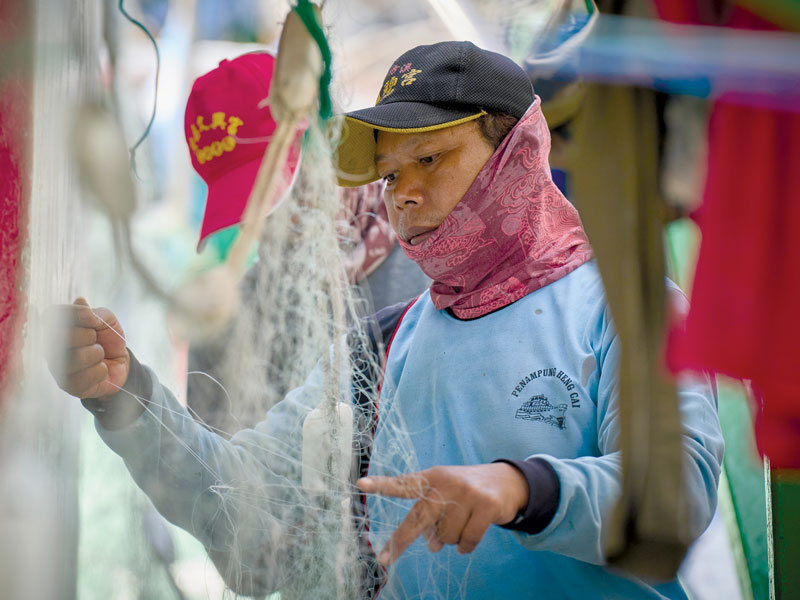 A migrant fisher untangles nets aboard a boat docked at Taichung Harbor. Some 7,000 Filipinos work long hours in difficult conditions on Taiwan-based fishing vessels. (Paul Jeffrey/Taiwan)