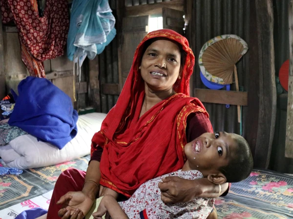 Abu Mosa Khan in his mother's arms at their home in Munshigonj district, Bangladesh, on Nov. 18, 2025. Through Father Robert McCahill's help, the family has access to free hospital treatment in Dhaka. Credit: Stephan Uttom Rozario<br />
