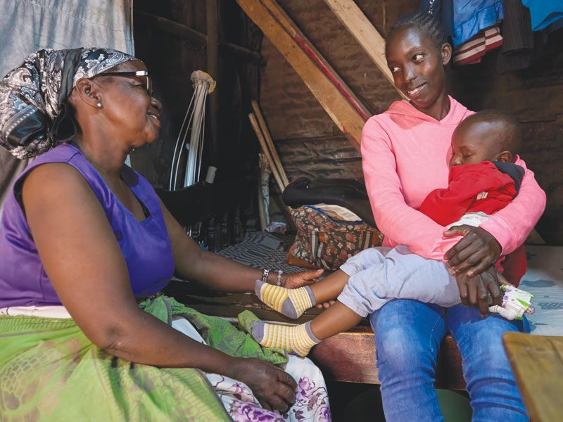 Josephine Kamau visits Stacy Adhiambo and 1-year-old Byalian at their home in the Mathare slum. Adhiambo was born HIV positive but didn't learn her status until 2005. She started on antiretroviral treatment, which later enabled her son to be born without the virus. (Paul Jeffrey/Kenya)