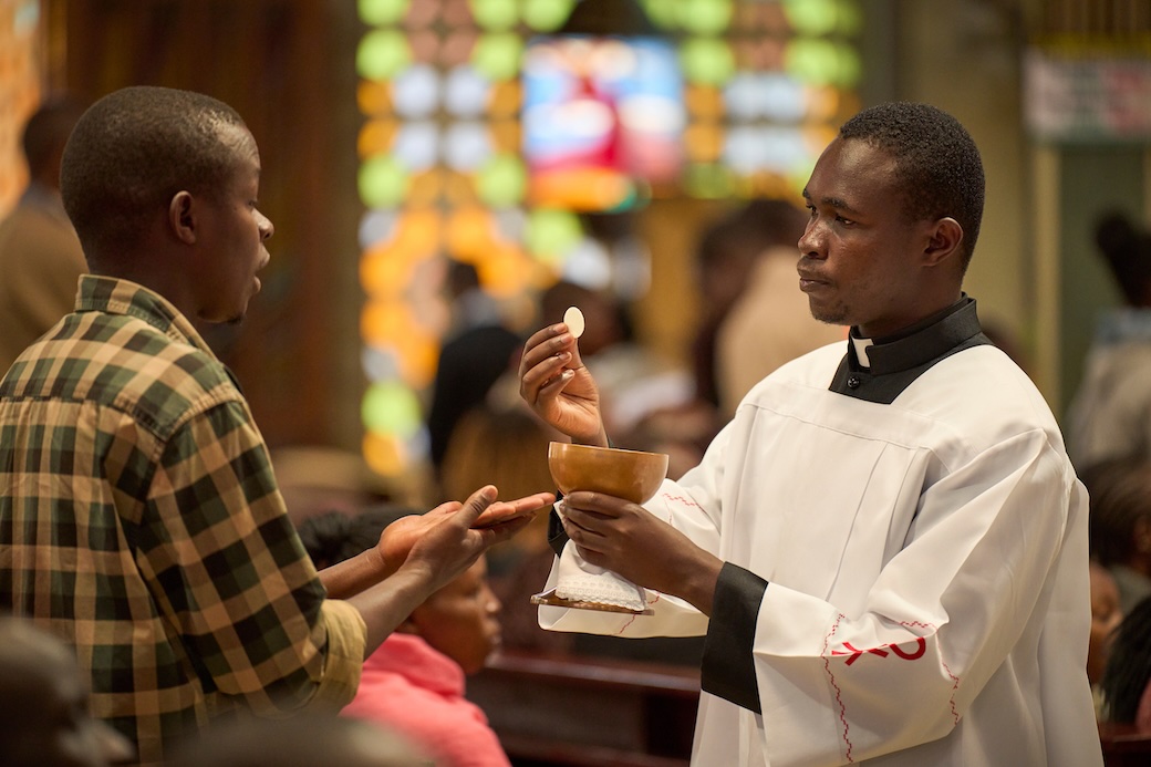 Michael Clement distributes Communication at St. Vincent Pallotti Church. Originally from Tanzania, Clement spends several hours a week at the Nairobi parish acquiring pastoral experience as part of his discernment process. (Paul Jeffrey/Kenya)