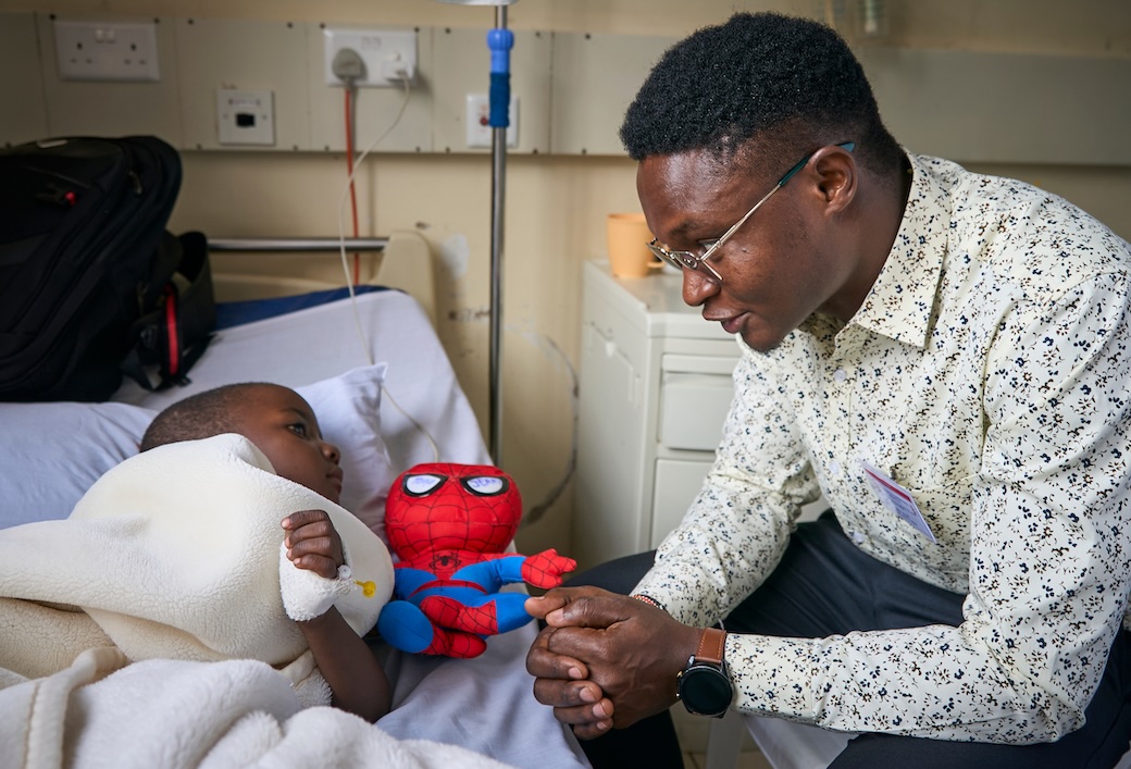 Alois Simpilisi, who is discerning a vocation with the Maryknoll Fathers and Brothers, visits a young patient at St. Francis Community Hospital in Nairobi. Seminarians offer several hours every week in volunteer activities to assist the sick and vulnerable. (Paul Jeffrey/Kenya)