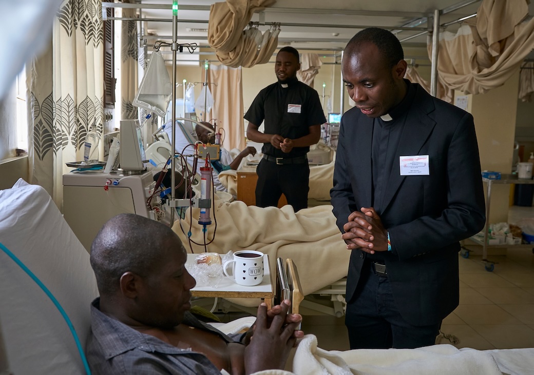 Frederick Richard Luhende and Babluu Ekama Kyamba (left, right), make pastoral visits to patients at St. Francis Community Hospital in Nairobi as part of their discernment process to become Maryknoll priests. (Paul Jeffrey/Kenya)