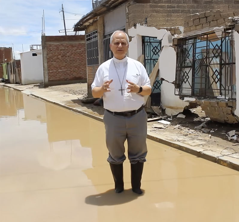 Then-Bishop Robert Prevost of Chiclayo, Peru, wades through floodwaters following heavy rains that struck northwestern Peru during March 2023 in this screenshot from a video by Cáritas Chiclayo. (NCR screengrab/Cáritas Chiclayo/Peru)